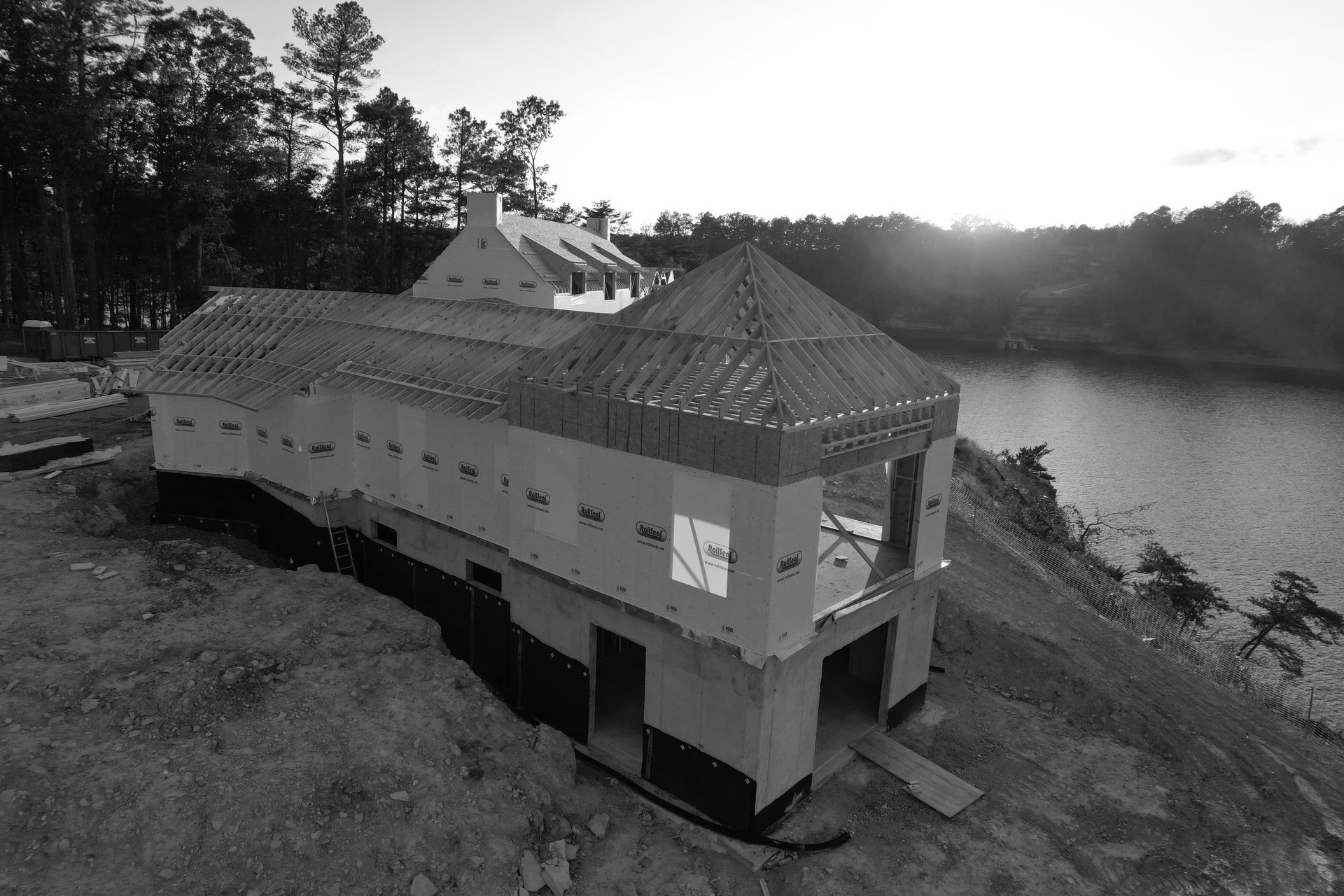 Partially built house with a lake in the background. Construction in progress, wood and framing visible.