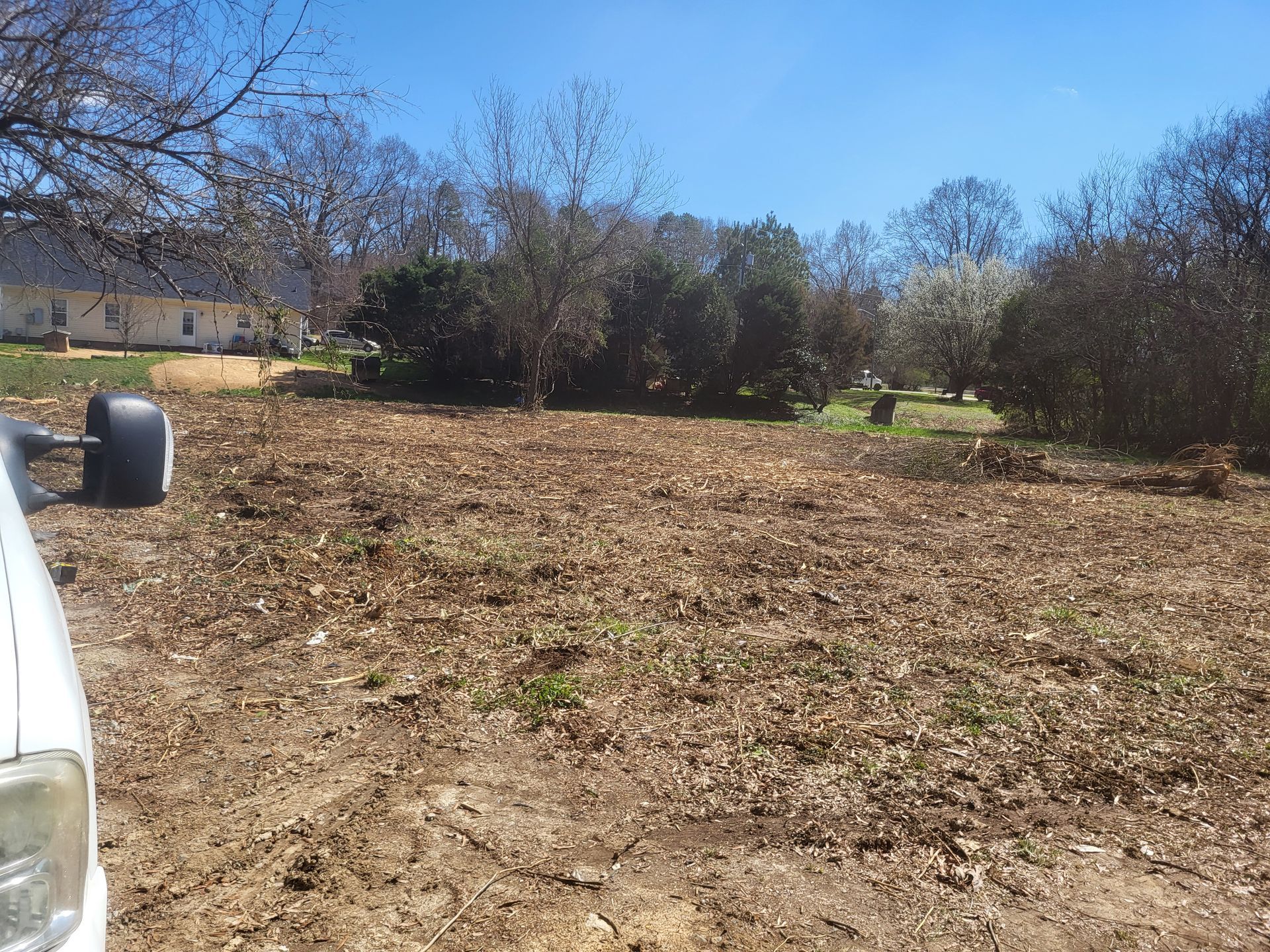 A white truck is parked in the middle of a dirt field
