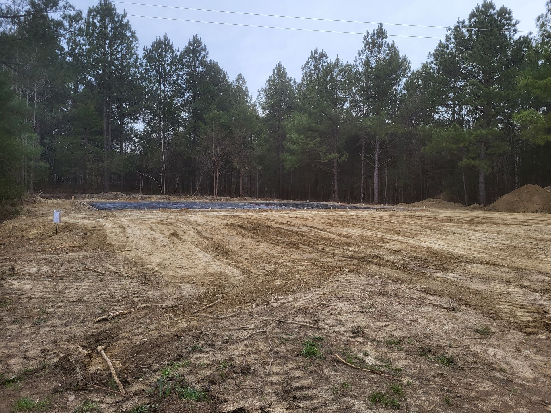 A large dirt field with trees in the background.