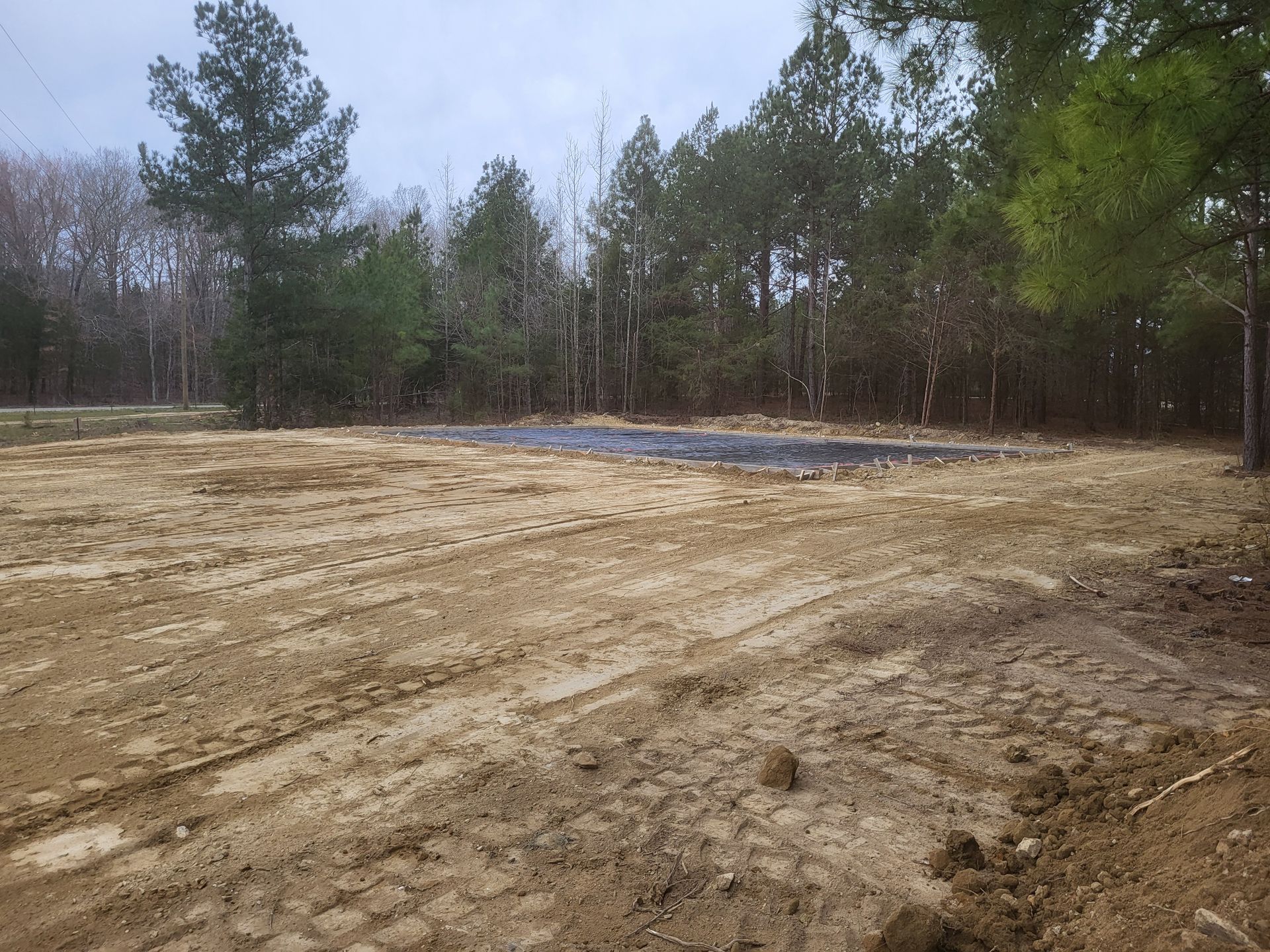 A large dirt field with trees in the background.