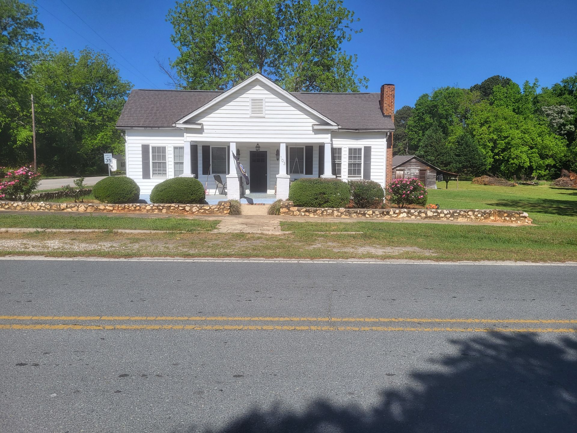 A small white house is sitting on the side of a road.