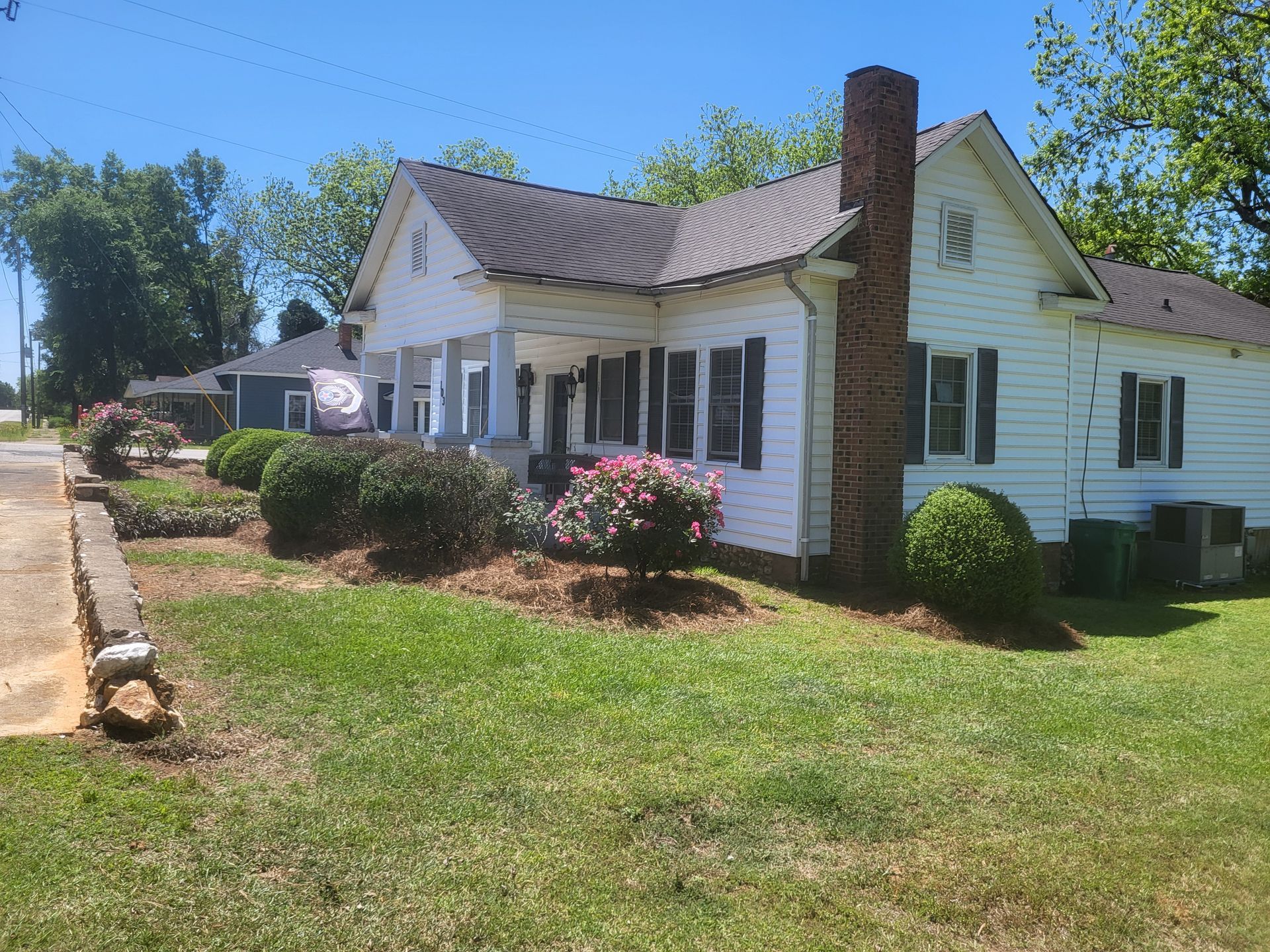 A white house with a brick chimney on the side of it