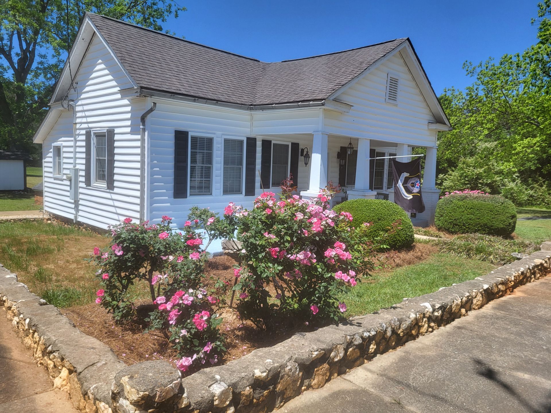 A white house with pink flowers in front of it
