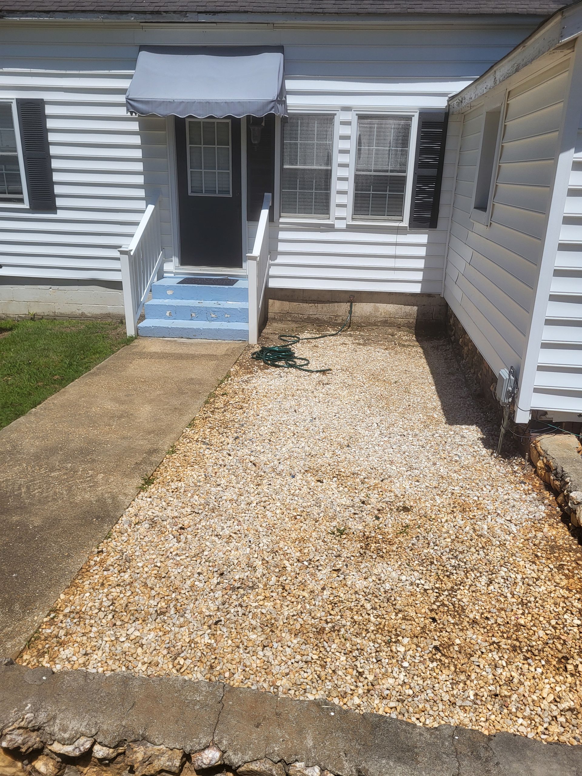 A white house with a gravel driveway in front of it