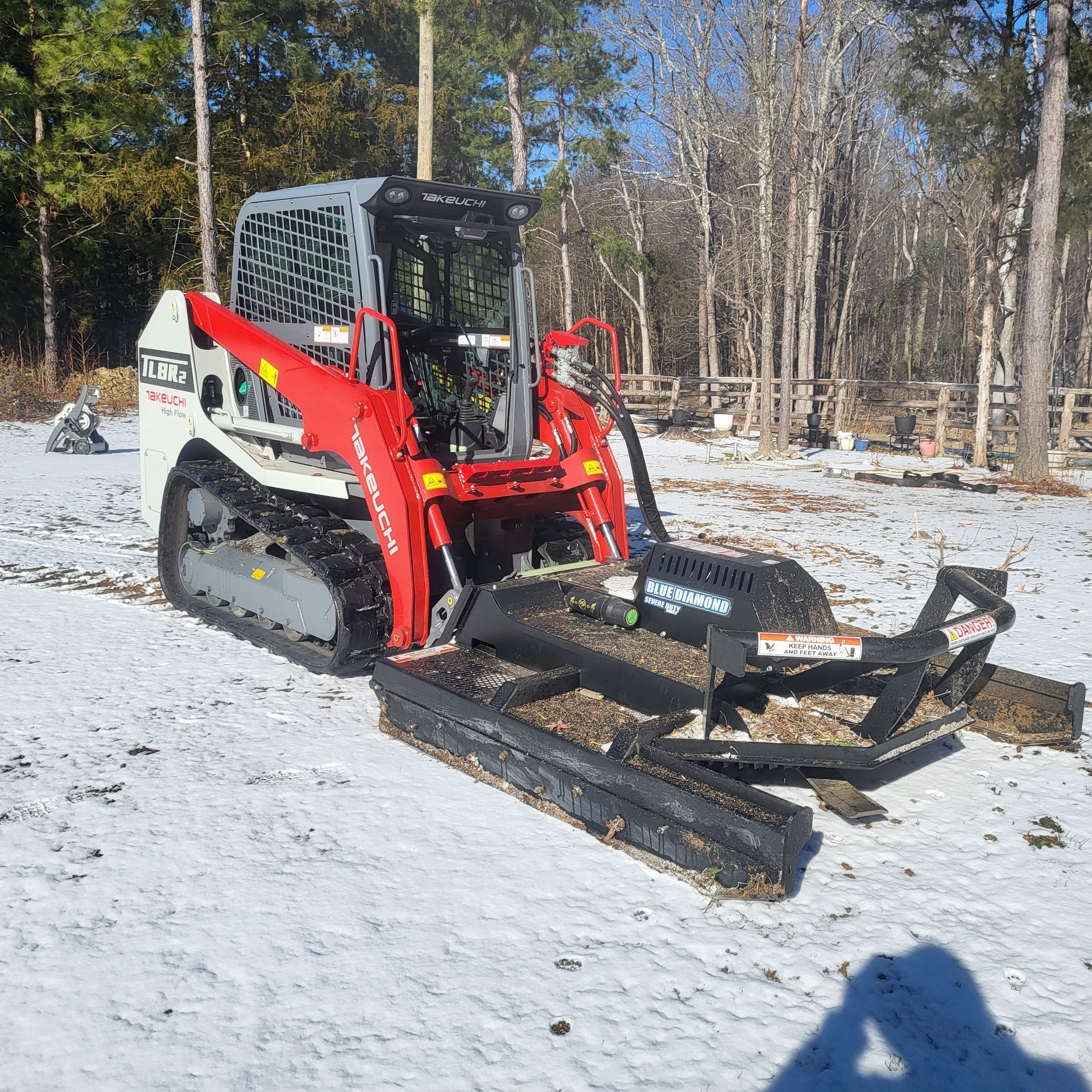 A red and white tractor is parked in the snow.
