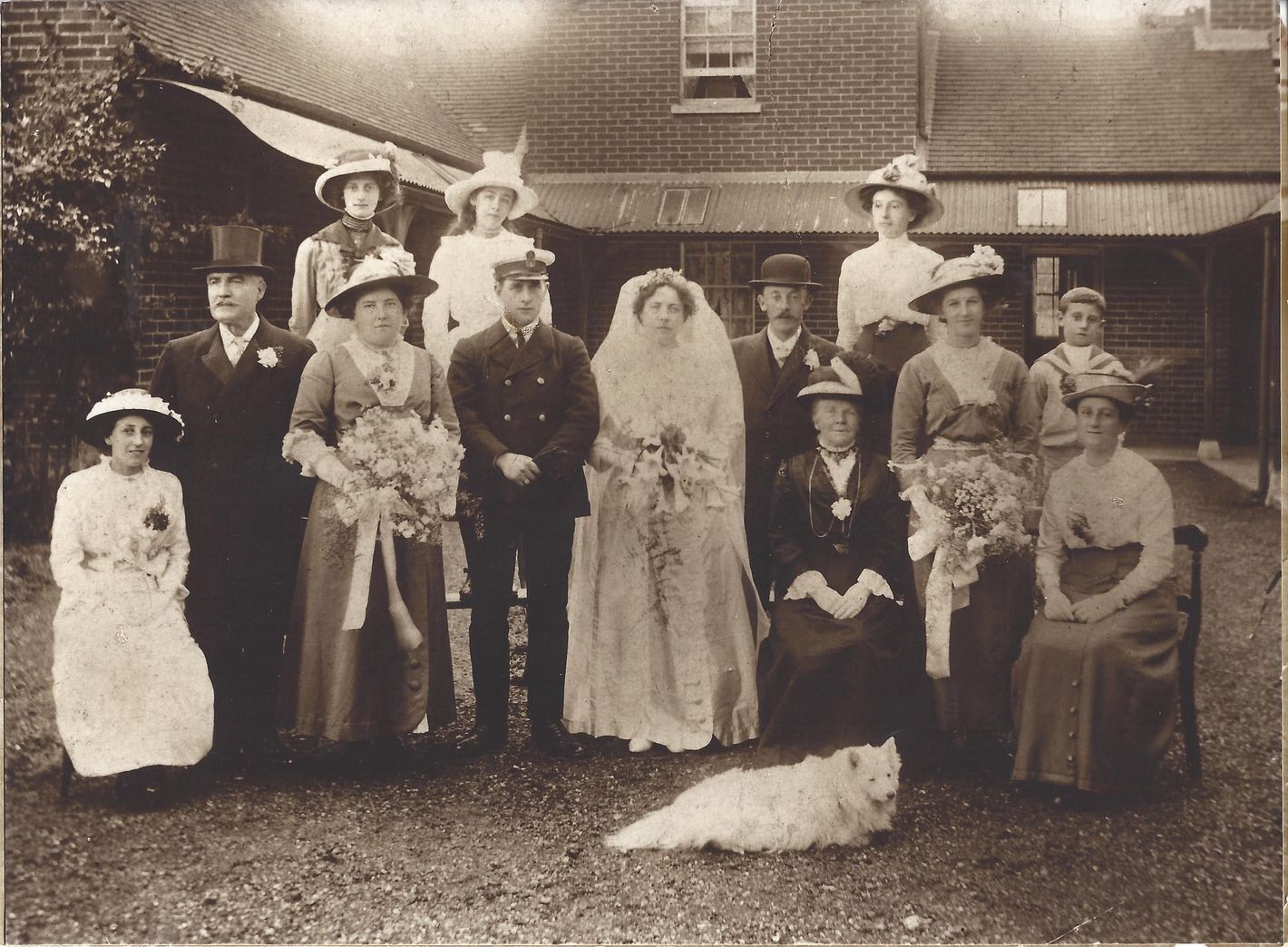 Group photo of a early 20th-century marriage, and a dog.