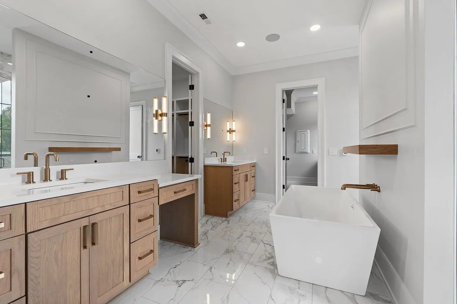 Bright, modern kitchen with white cabinets, gray island, stainless steel appliances, and dark wood floors.
