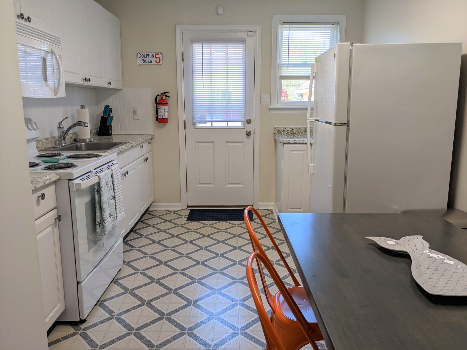 A kitchen with a stove , refrigerator , microwave , sink and table.