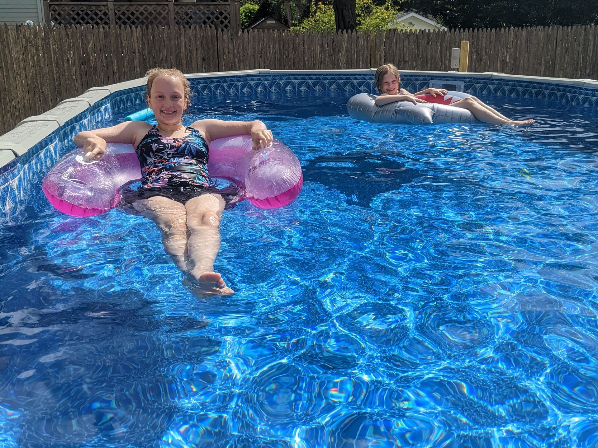 Two children are floating in a swimming pool.