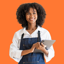 a woman in an apron is holding a tablet and smiling .