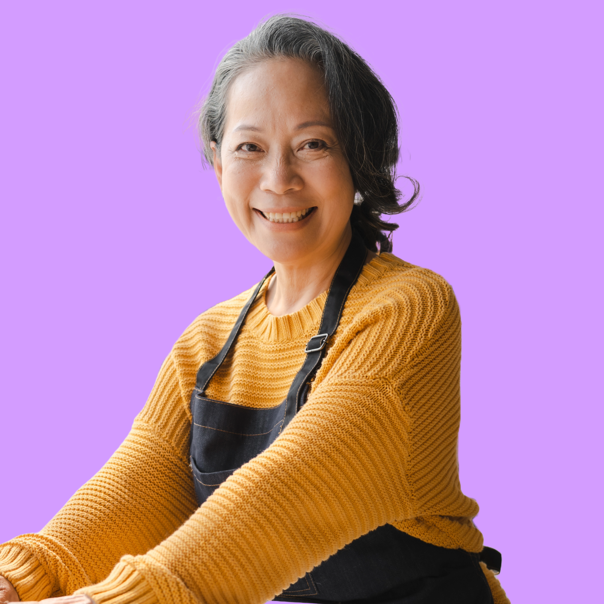 a woman in a yellow sweater and black apron is smiling