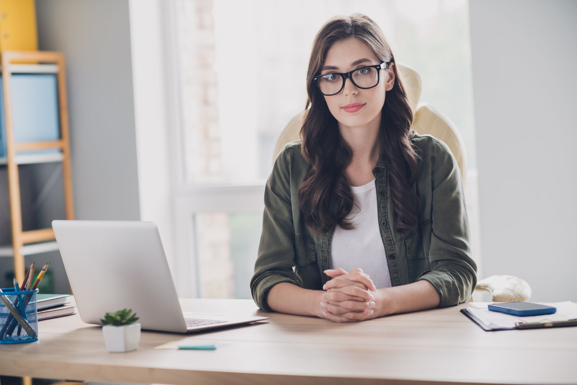 A woman is sitting at a desk in front of a laptop computer.