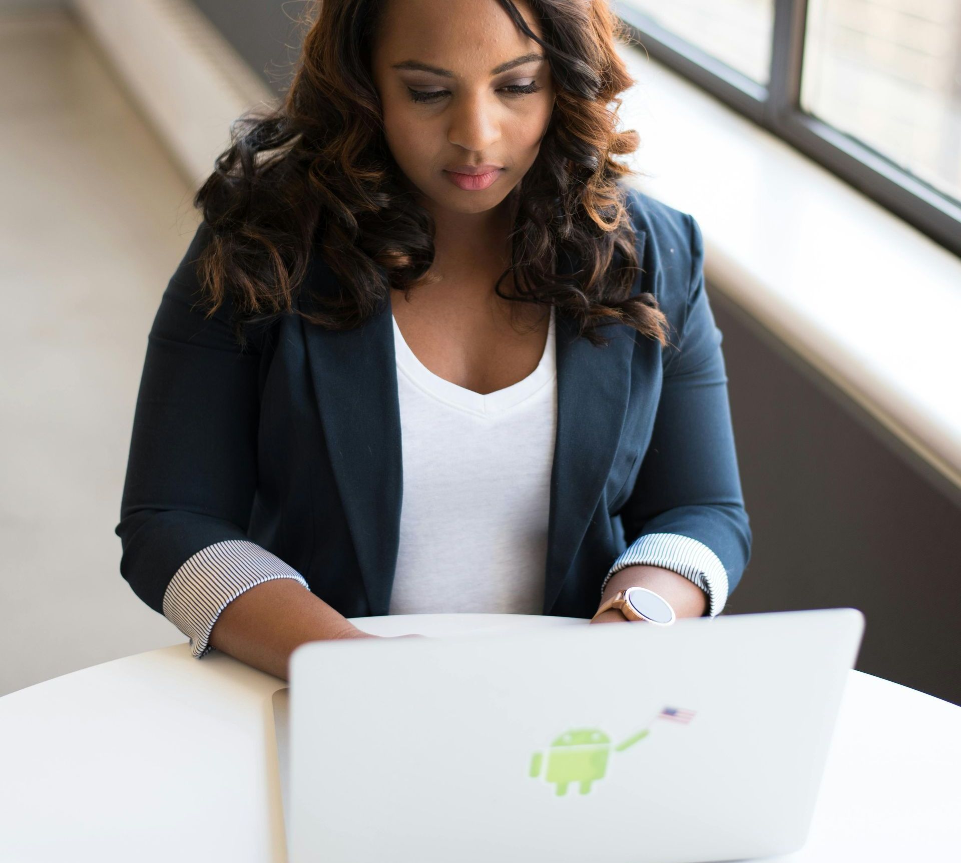 A woman is sitting at a table using a laptop computer.