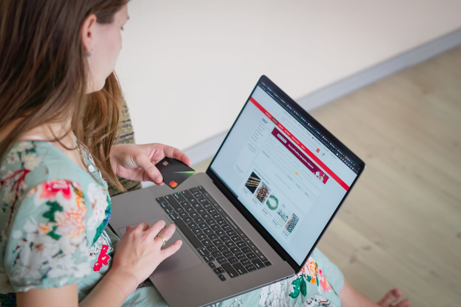 Woman using a laptop on the floor, viewing a website on the screen
