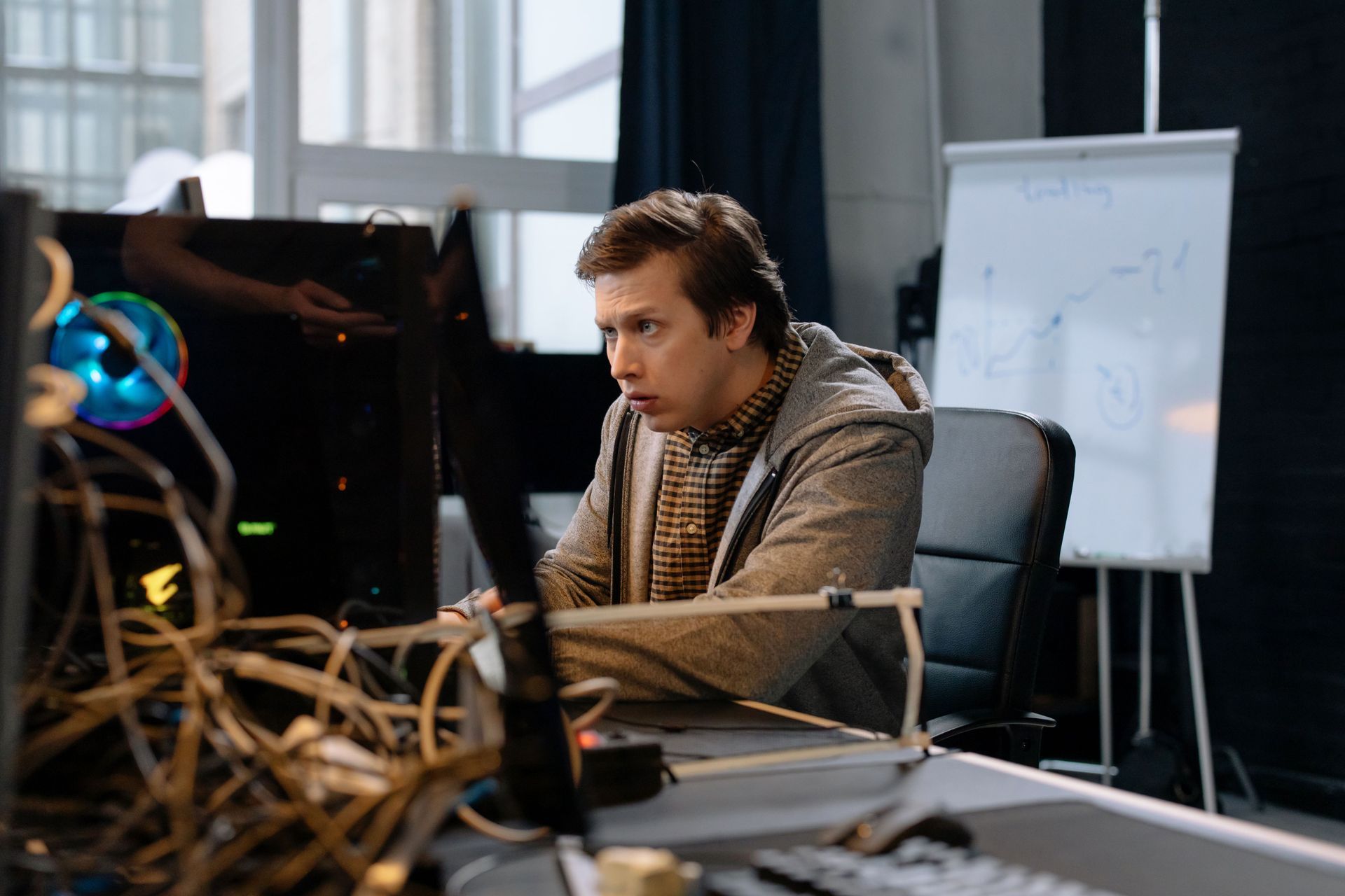 Person working at a desk with computer monitors and cables in an office