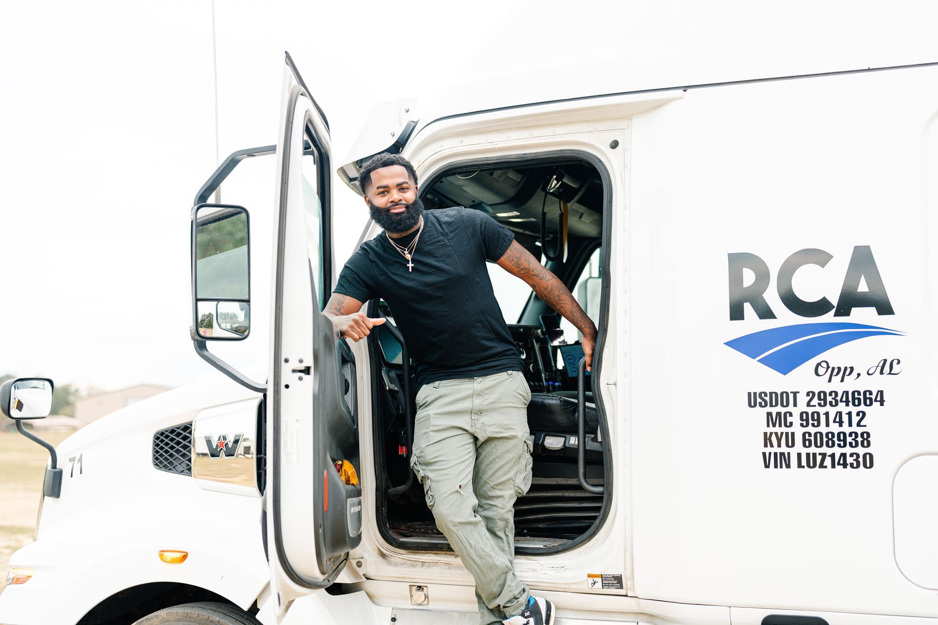 A person standing in the open door of a white semi-truck with 
