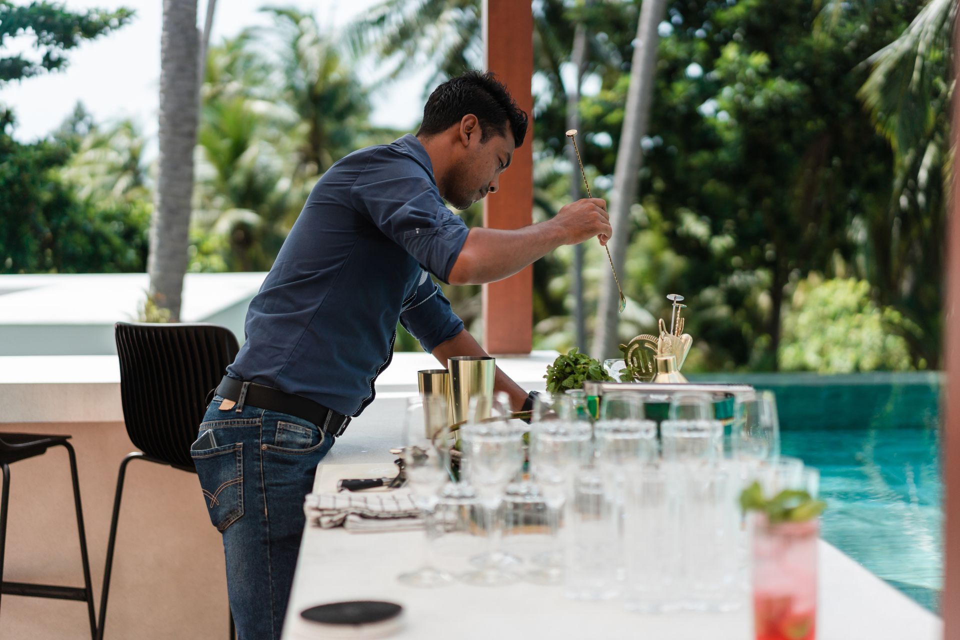 A man is standing at a bar making a drink.