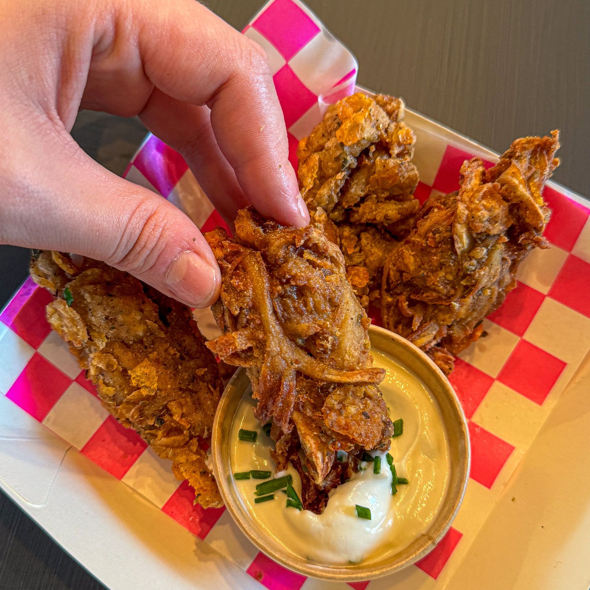 A person is taking a piece of fried food from a plate.