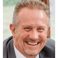 A man in a suit and tie is smiling for the camera.