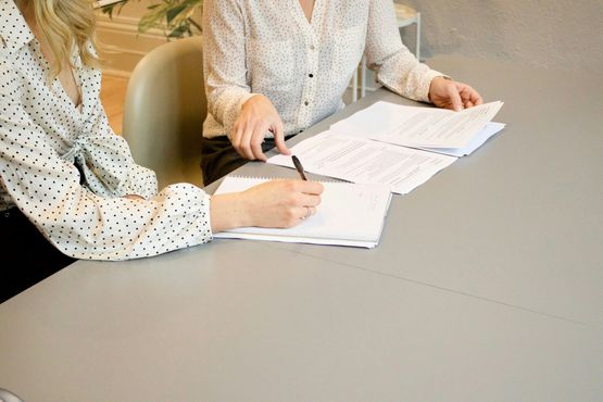 Two people reviewing and writing on documents at a table.