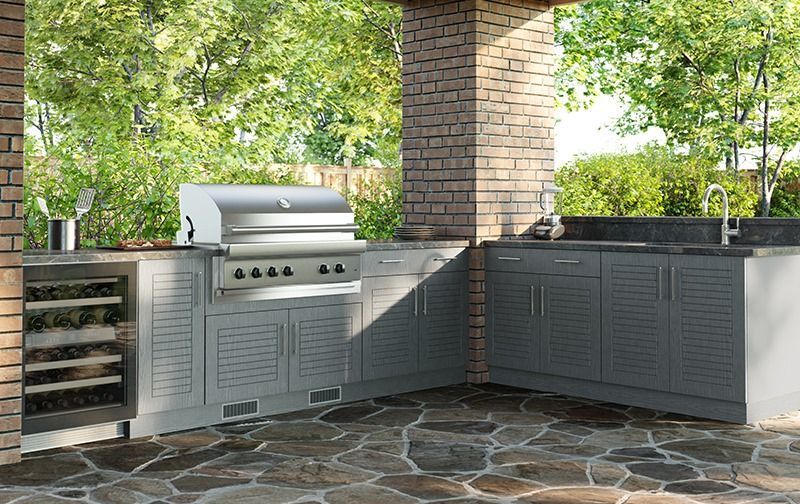 An outdoor kitchen with a grill , sink , and refrigerator.