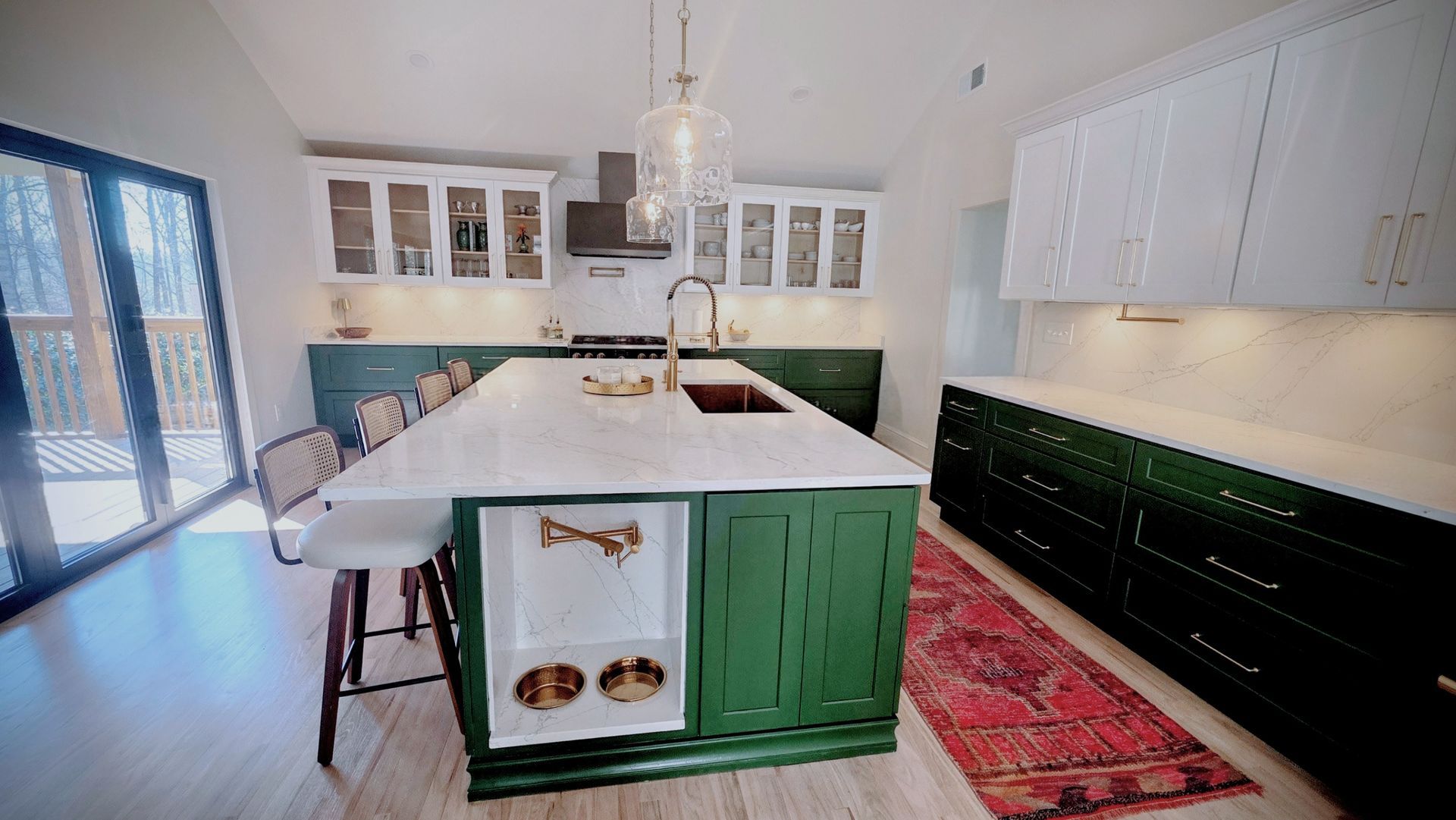 Green and white kitchen with a large island and dog feeding station.