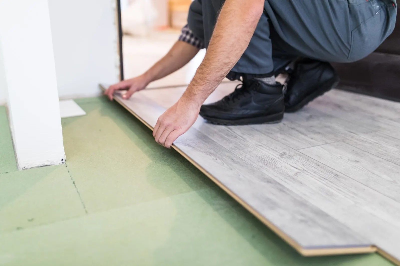 A man is installing a wooden floor in a room.