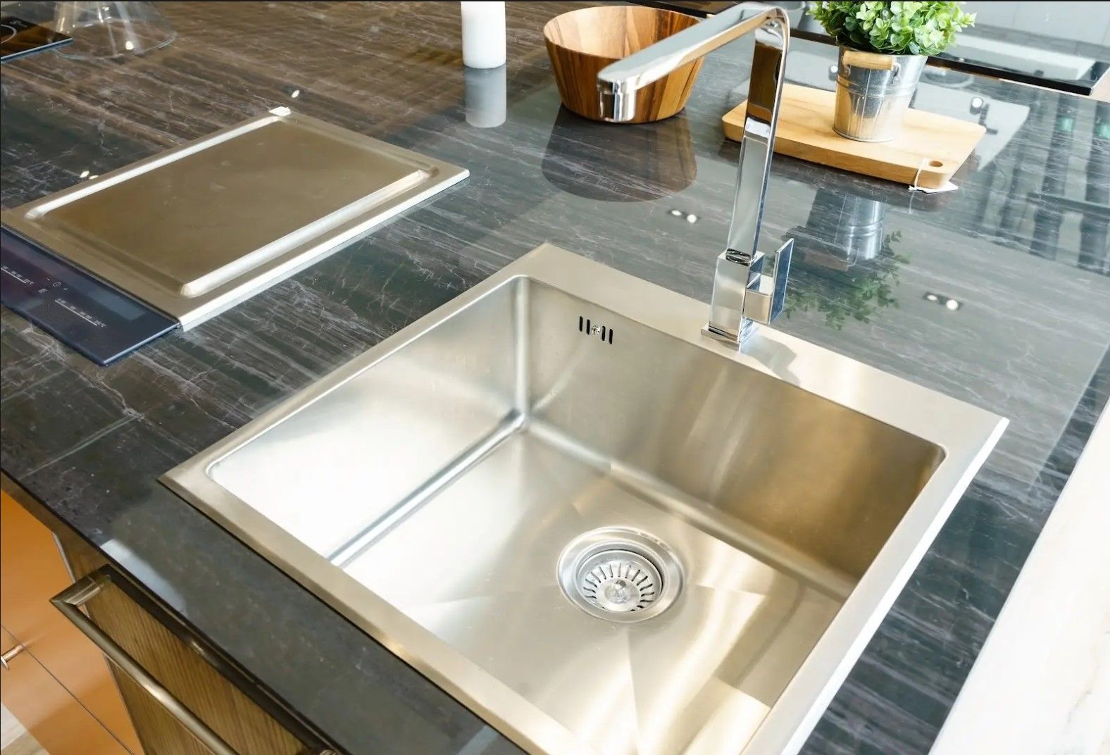 A stainless steel sink is sitting on top of a black granite counter.