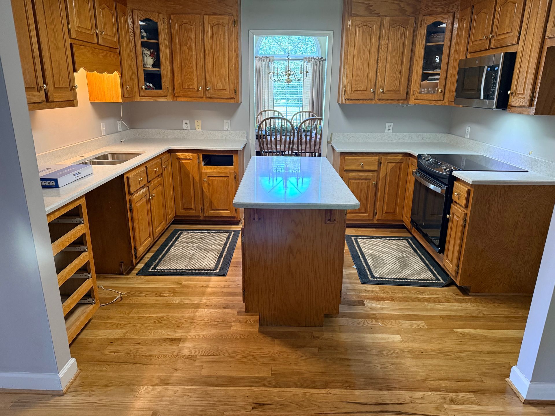 Kitchen with wooden cabinets, white countertops, central island, and a window over the sink.