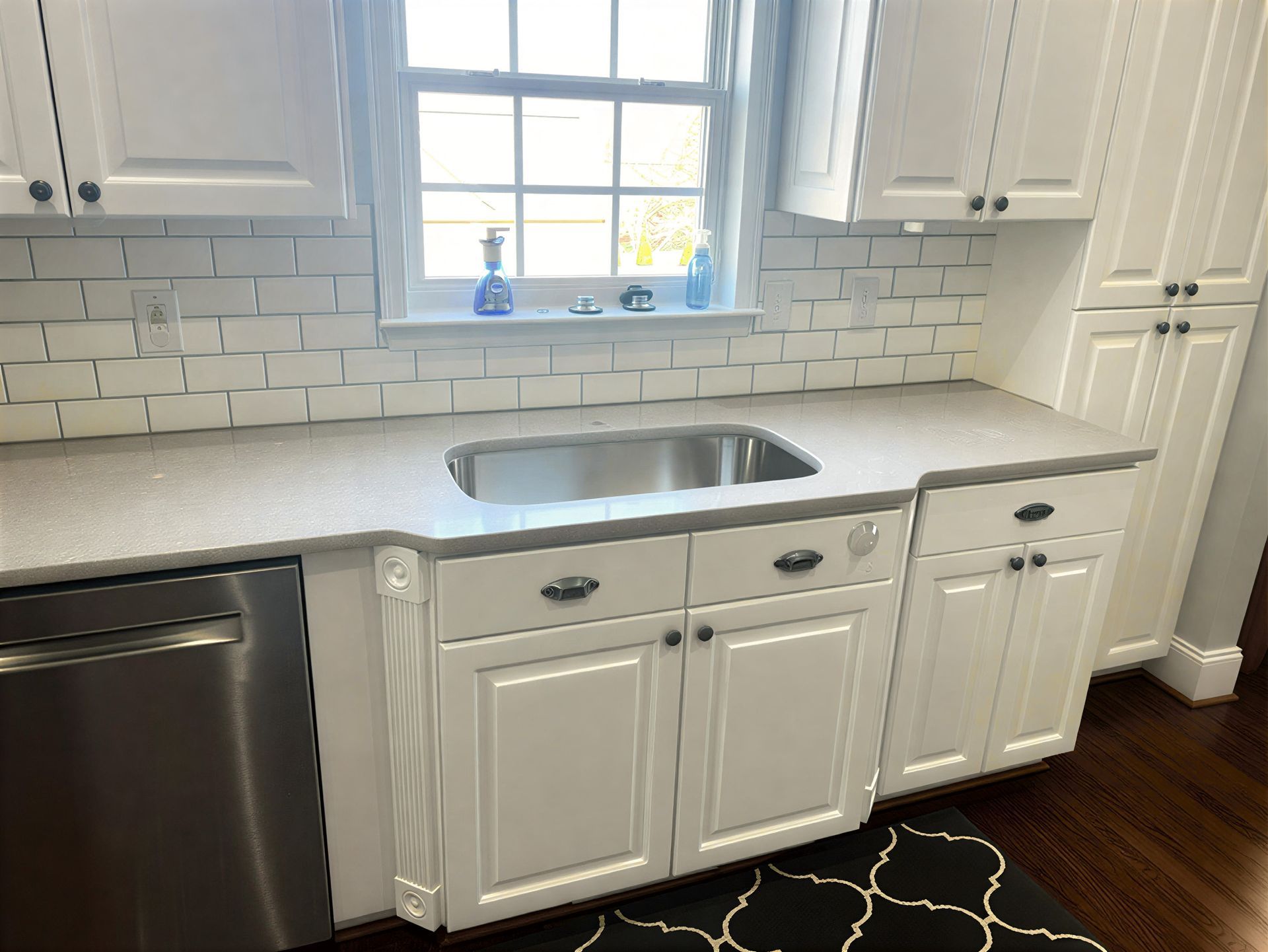 White kitchen with stainless steel appliances, white cabinets, and gray countertop.