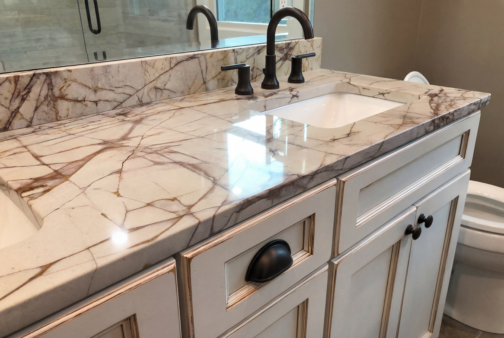 Bathroom vanity with white cabinets, marble countertop, and black faucet.