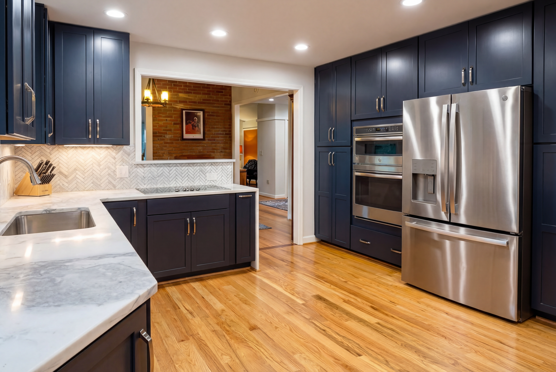 Modern kitchen with navy blue cabinets, stainless steel appliances, and wood floors.