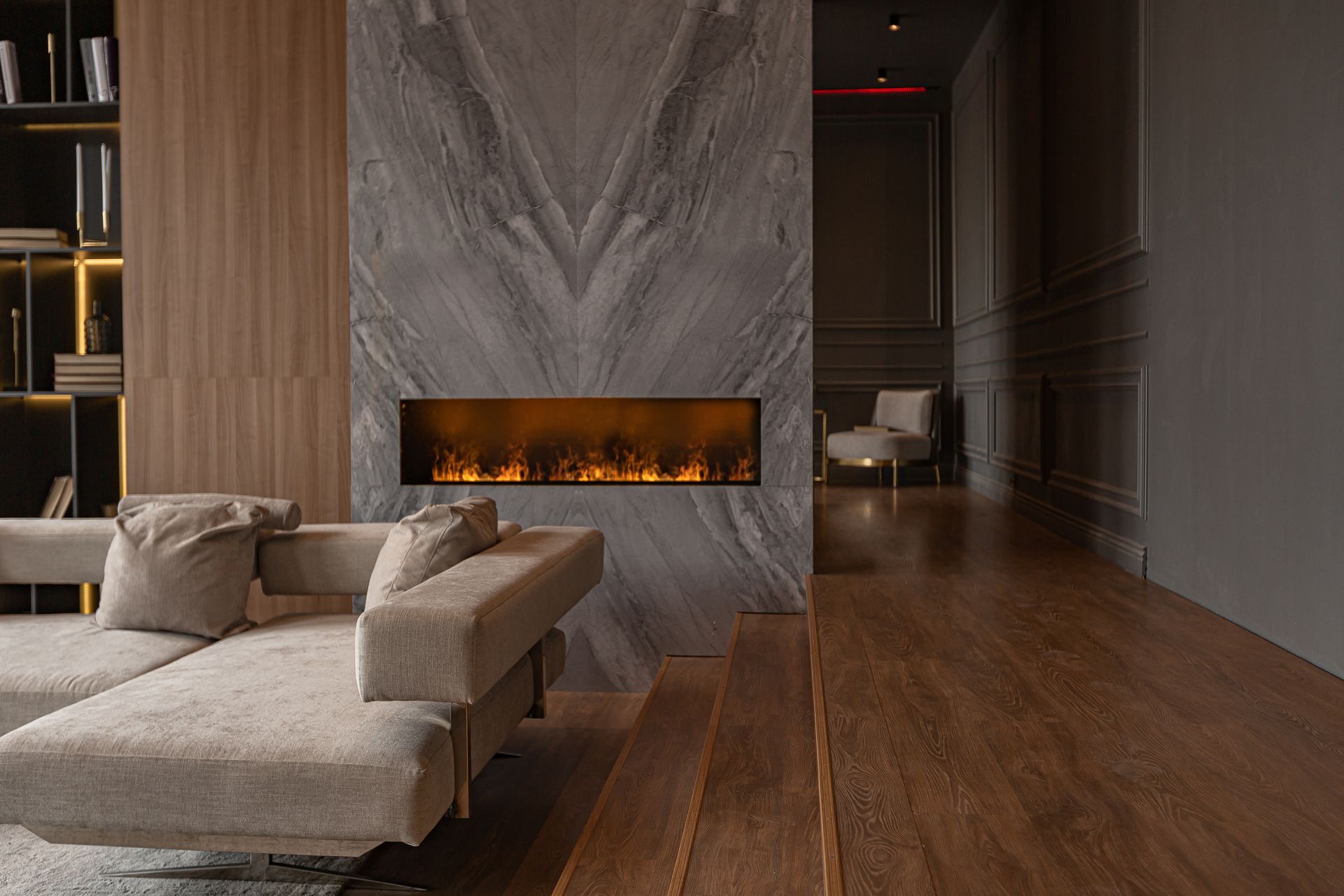 Living room with modern fireplace, sofa, wooden floor, and gray marble wall.