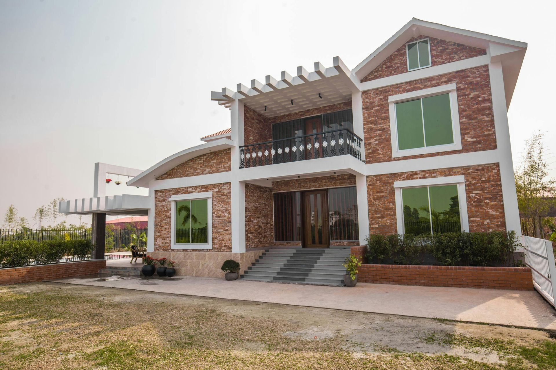 A large brick house with a lot of windows and a balcony and custom concrete sidewalk