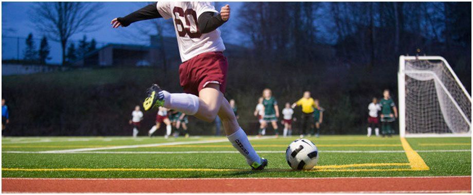 A person is kicking a soccer ball on a field.