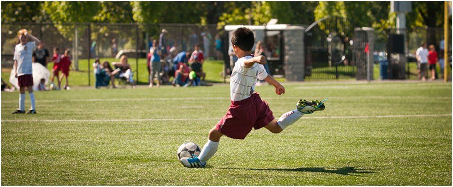 A young boy is kicking a soccer ball on a field.