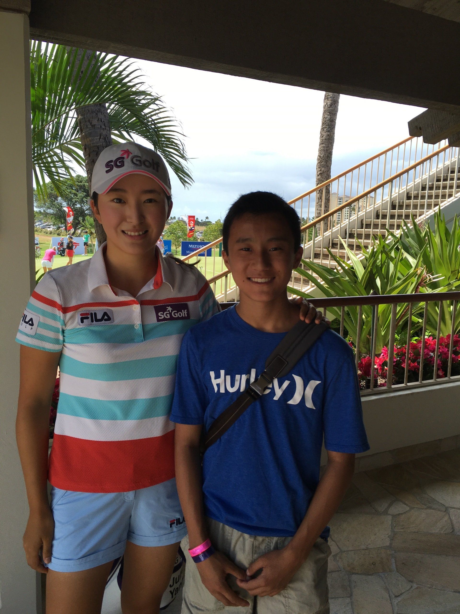 A boy wearing a hurley shirt stands next to a woman