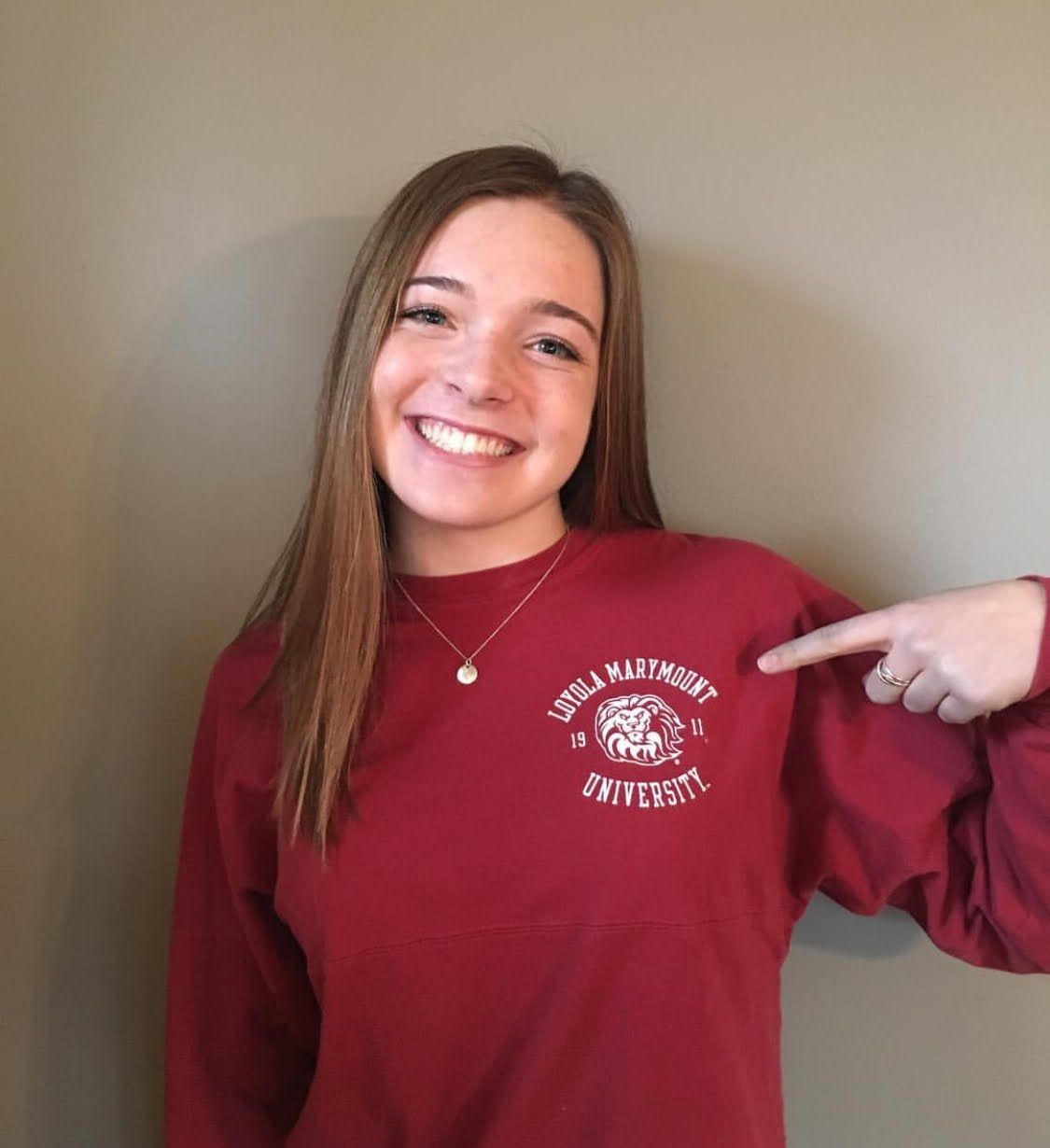 A girl wearing a maroon sweatshirt with a lion on it