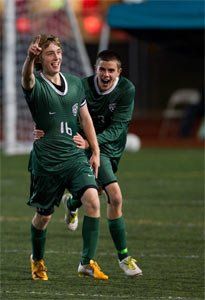 Two soccer players are celebrating a goal on the field.