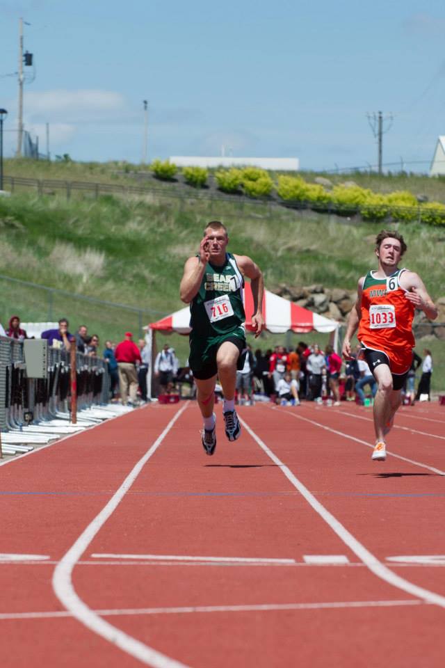 Two men are running on a track and one has the number 1331 on his shirt