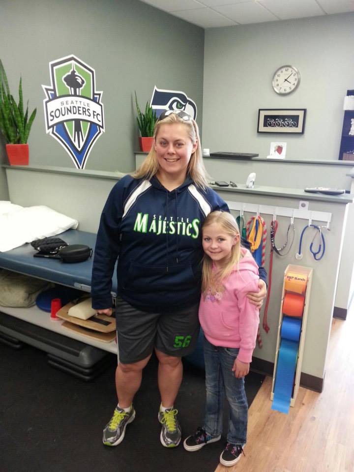 A woman wearing a seahawks shirt stands next to a little girl
