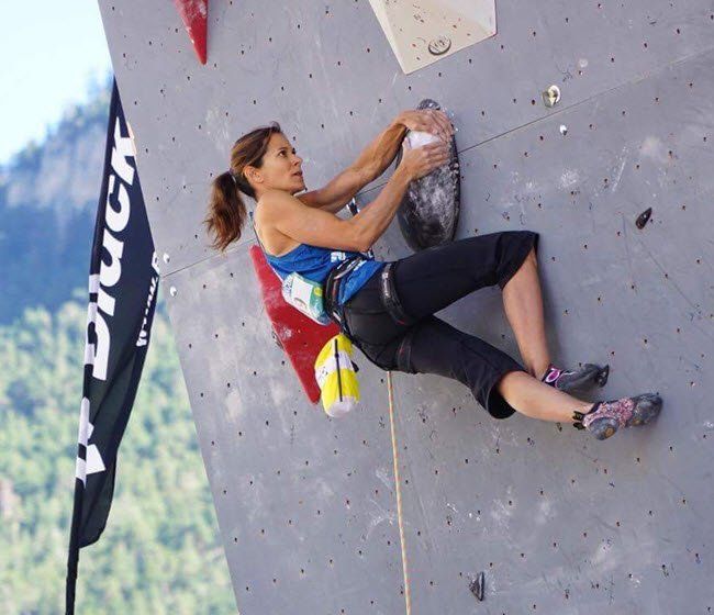 A woman is climbing a wall with a black diamond flag in the background
