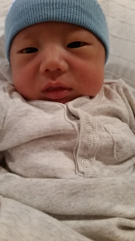 A close up of a baby wearing a blue hat.