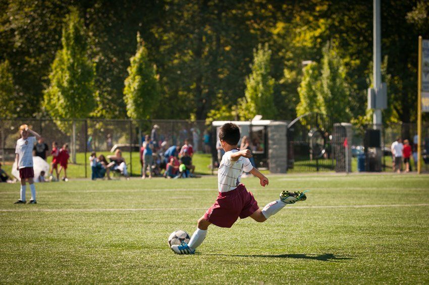 A young boy is kicking a soccer ball on a field.