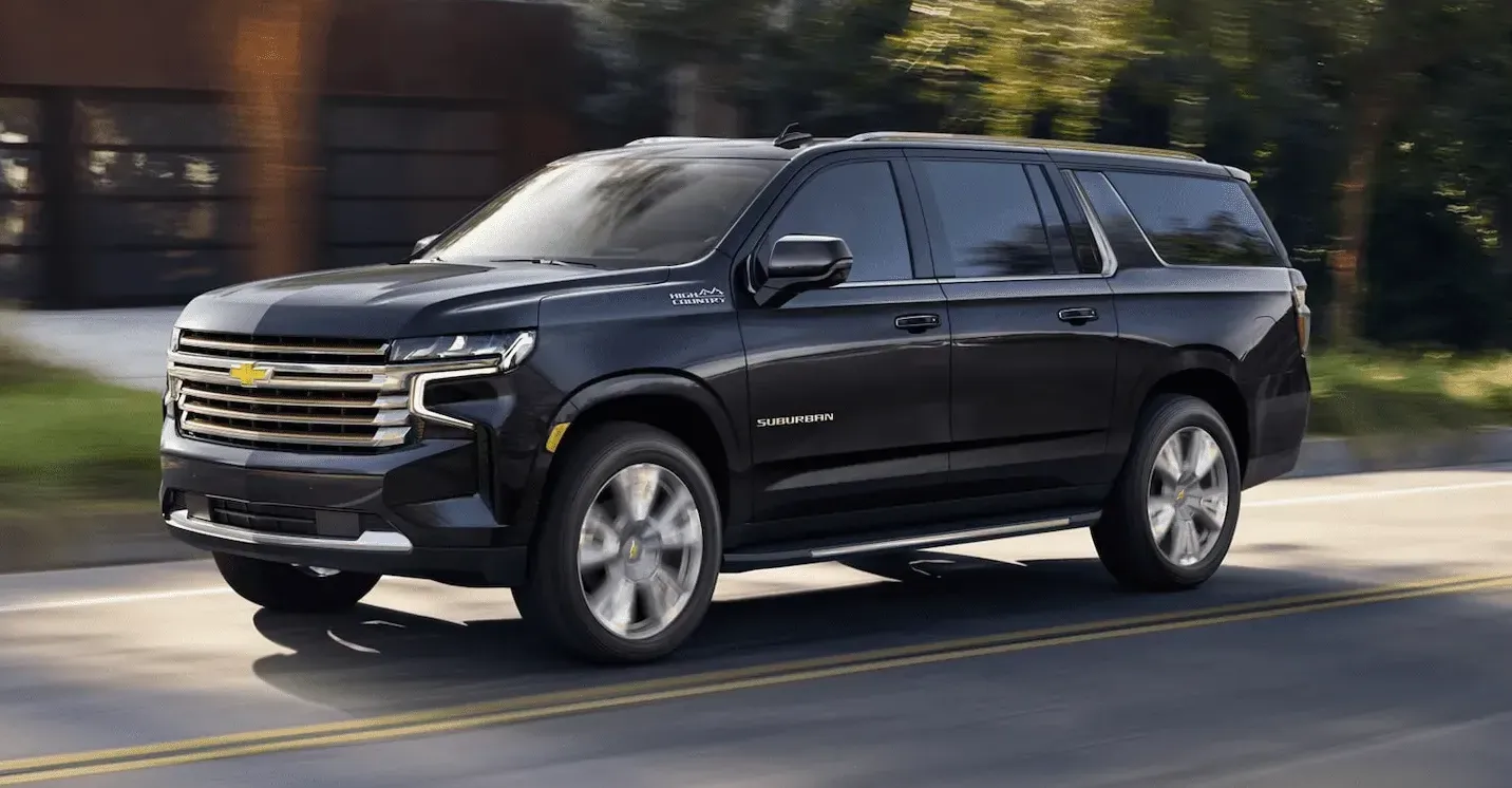 A black chevrolet suburban suv is driving down a road.