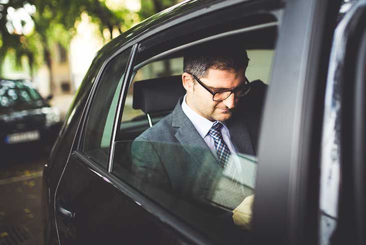 A man in a suit and tie is sitting in the back seat of a car.