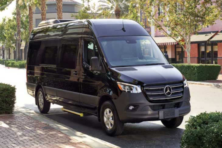 A black mercedes sprinter van is parked on the side of the road.
