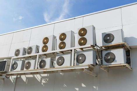 A row of air conditioners on the side of a building.