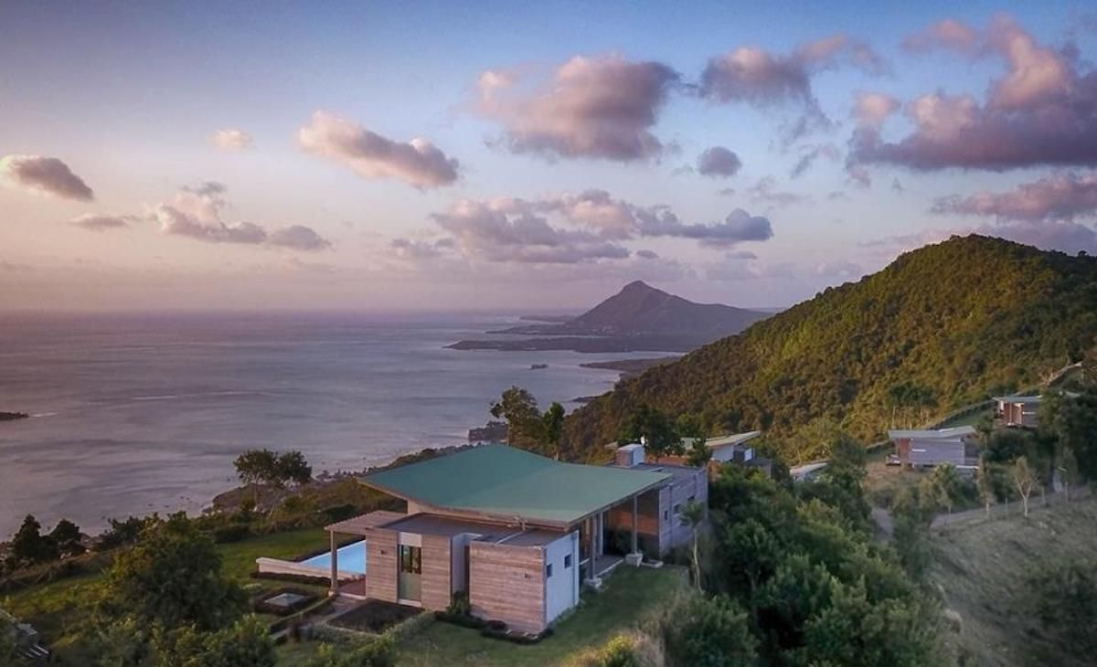 An aerial view of a house on top of a hill overlooking the ocean in Mauritius