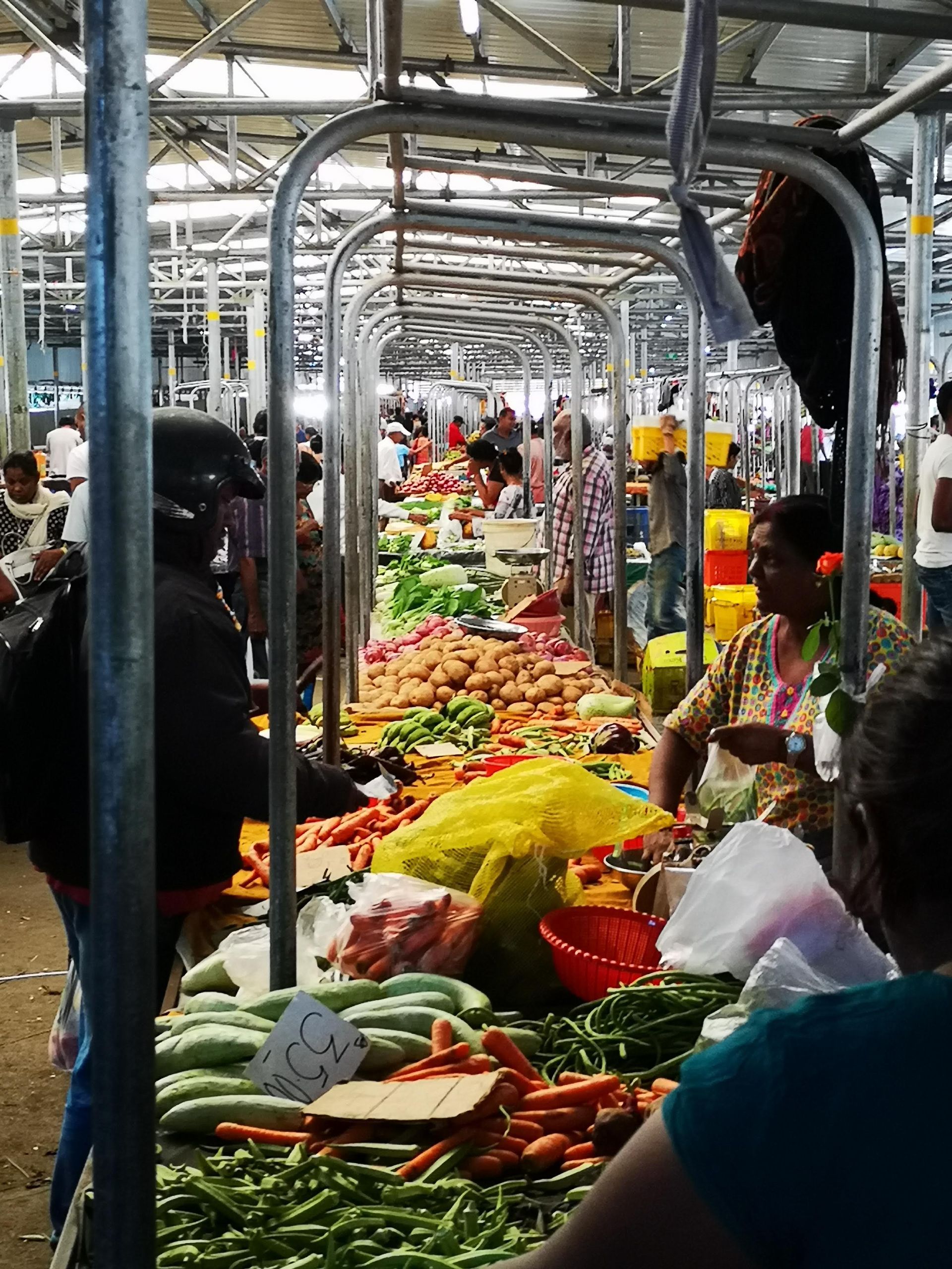 A pile of tomatoes next to a bowl of chilli peppers in Port Louis Markets